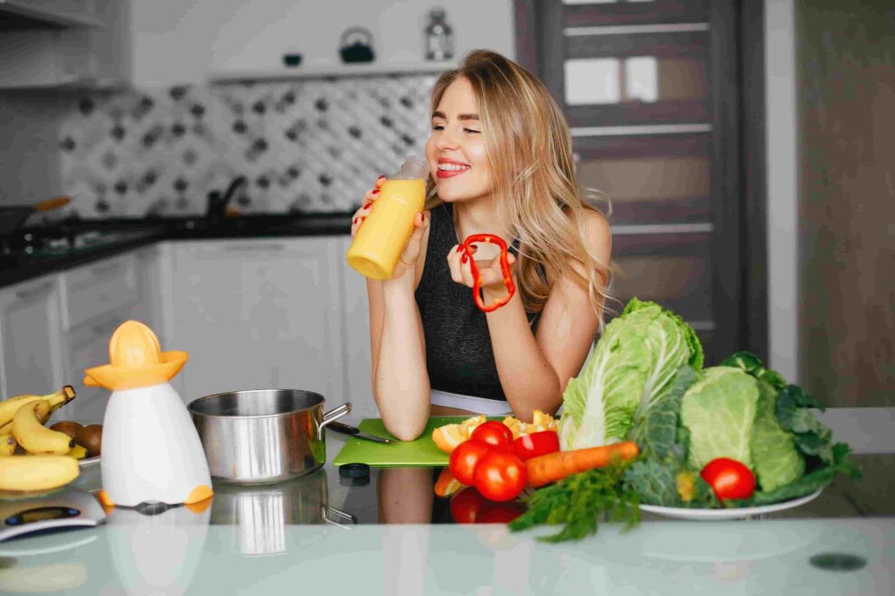 mulher de vestido comendo verduras e legumes sobre um balcão