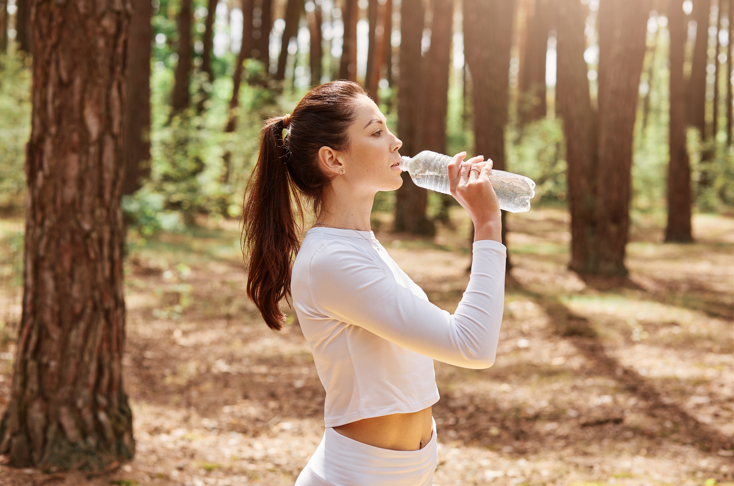Close em mulher bebendo água com roupas esportivas em parque